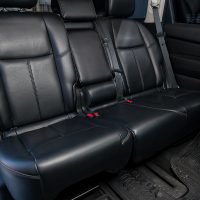 Clean after washing the rear passenger seats of matte black genuine leather inside the interior of an expensive SUV, preparation before selling the car.